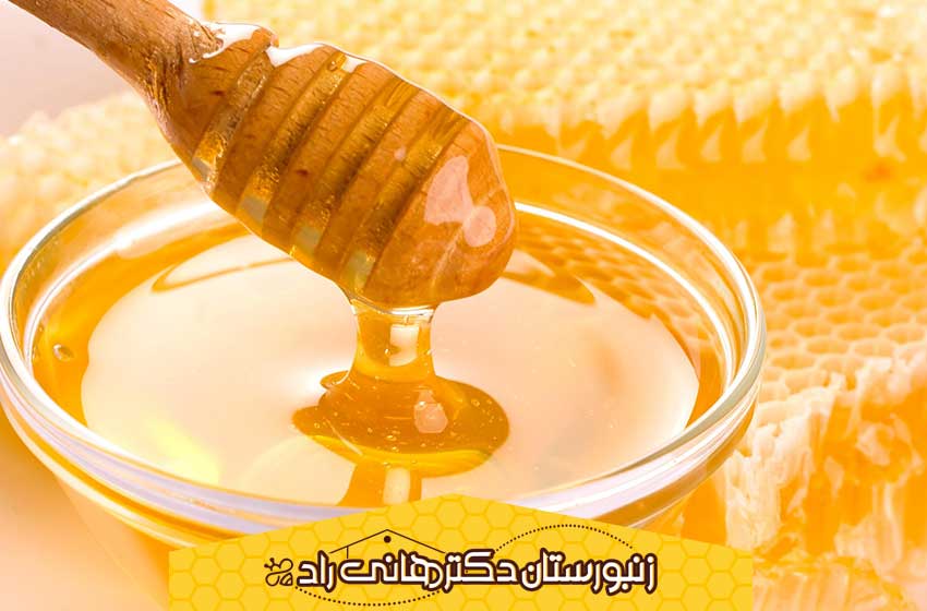 قاشق عسل درون ظرف عسل که عسل ها حباب دارد.